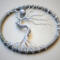 Handmade art featuring a silver tree with twisted roots and branches inside a circular rustic frame, topped with a pearl-bodied owl charm.
